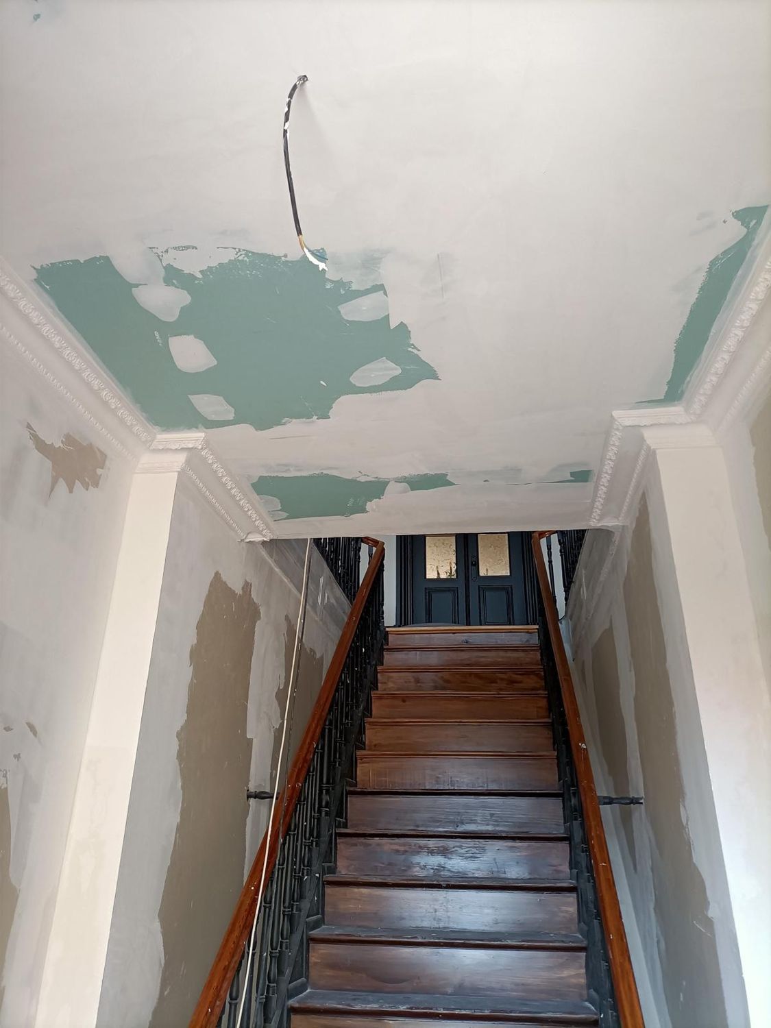 A escada de entrada durante a obra, com paredes por pintar e o teto remendado